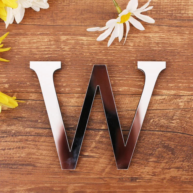 Letter W in silver mirror acrylic, 20 cm, on a wooden table with flowers