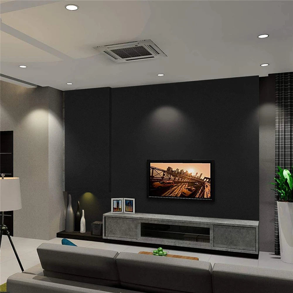 Wohnzimmer mit mattschwarzer Wand hinter dem Fernseher und niedrigem Schrank