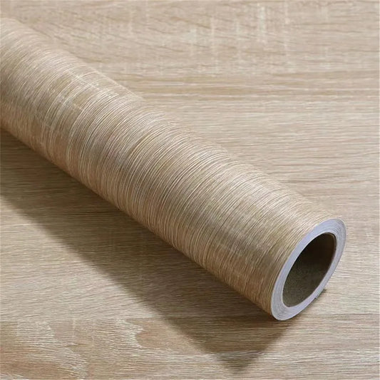 Roll of light grey beige wood effect adhesive vinyl resting on vinyl laid out flat