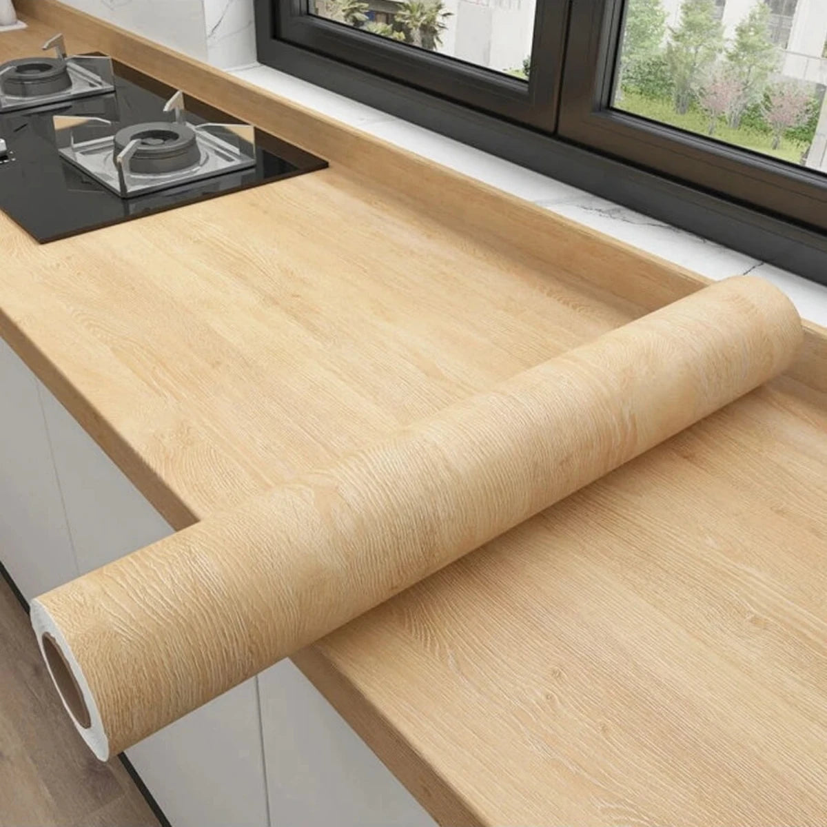 Worktop by the window covered in honey yellow wood effect vinyl, with the roll on top