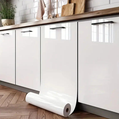 Küchentüren mit glänzender weißer Möbelfolie beklebt, an die eine Rolle gelehnt ist