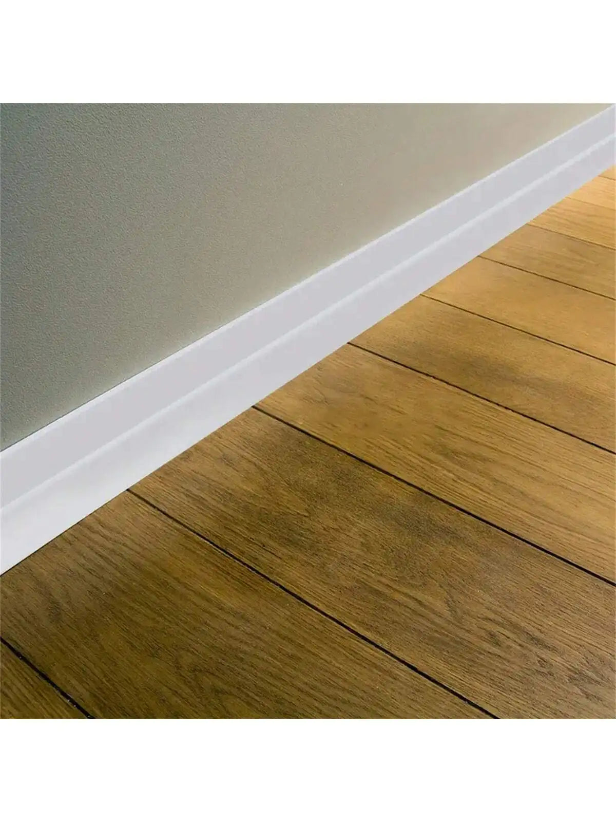 Weiße selbstklebende Zierleiste am Fuß einer Wand über einem Holzboden