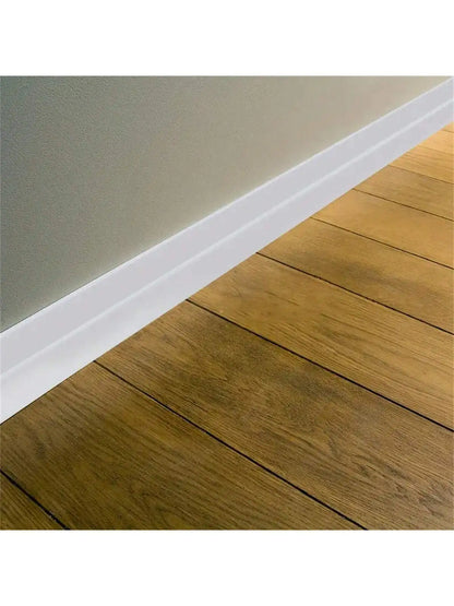 Weiße selbstklebende Zierleiste am Fuß einer Wand über einem Holzboden