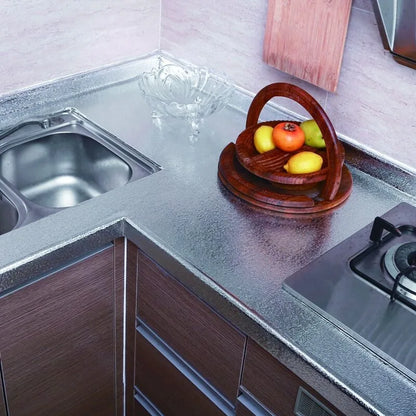 Küchenecke mit Spüle, gemusterter silberner Arbeitsplatte und einem Obstkorb