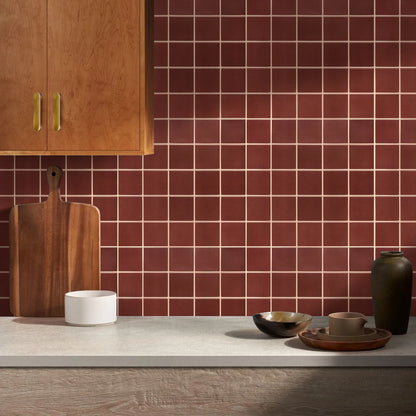 Kitchen splashback covered in red self-adhesive square panels, beside a wooden cabinet