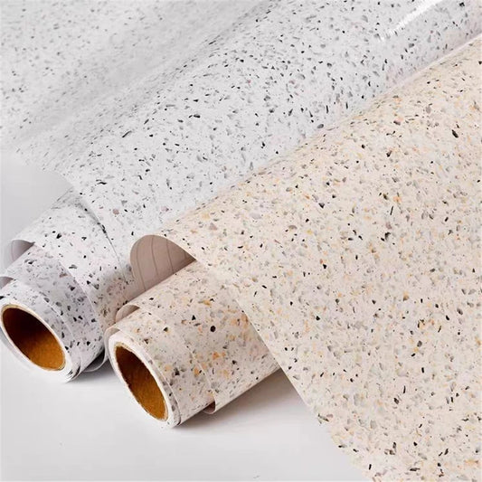 Zwei Rollen Möbelfolie in Terrazzooptik, weiß und beige, mit glänzender Oberfläche auf weißem Hintergrund