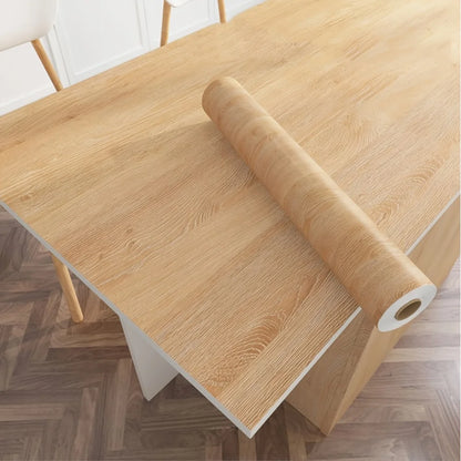 Roll of light natural wood effect self-adhesive vinyl on a table