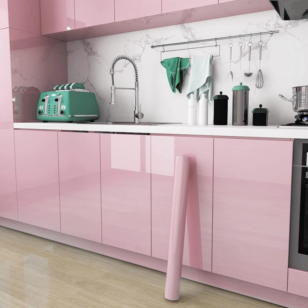 Küche mit Türen, die mit glänzender rosa Möbelfolie beklebt sind, und eine an die Wand gelehnte Rolle