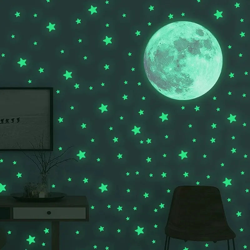 Green glow in the dark moon and stars on a dark wall, with the silhouette of a chair and a small table