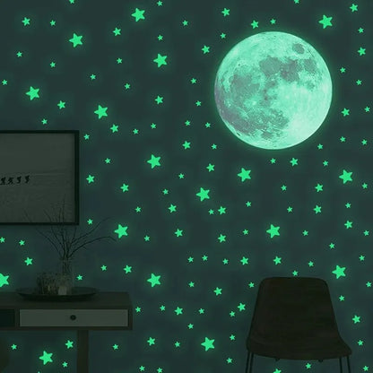 Green glow in the dark moon and stars on a dark wall, with the silhouette of a chair and a small table