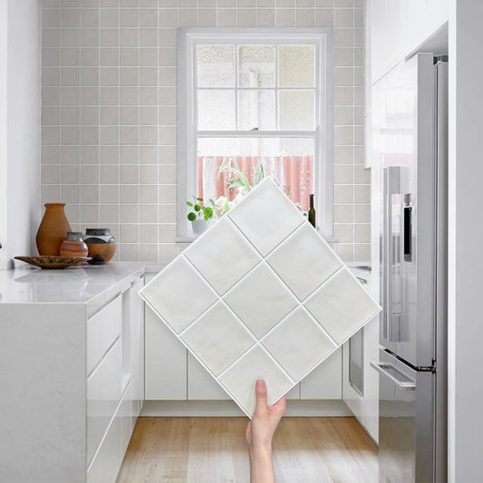 A hand holds a nine-square sheet in front of a kitchen with a tiled wall