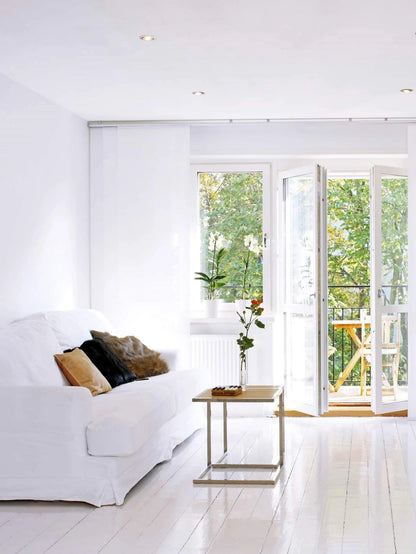 Helles Wohnzimmer mit weißen Wänden und Sofa und einer Balkontür