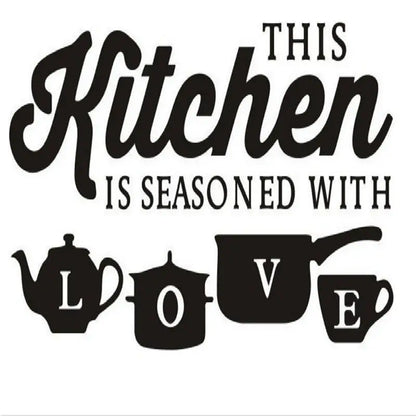 Musta tarra, jossa teksti ”This kitchen is seasoned with love” sekä teekannun, kattilan, paistinpannun ja kupin siluetit