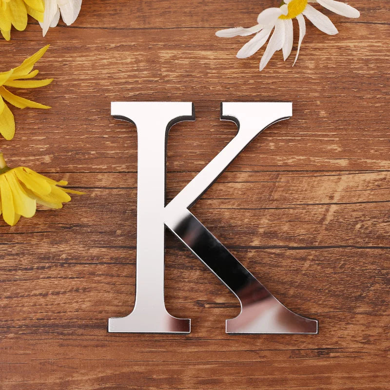 Letter K in silver mirror acrylic, 20 cm, on a wooden table with flowers