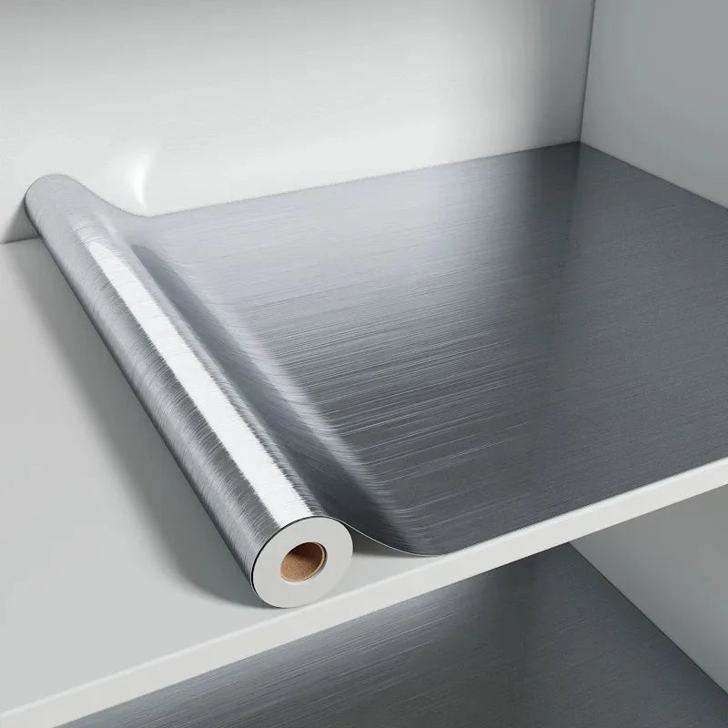 Roll of stainless steel effect adhesive vinyl unrolled on a white shelf