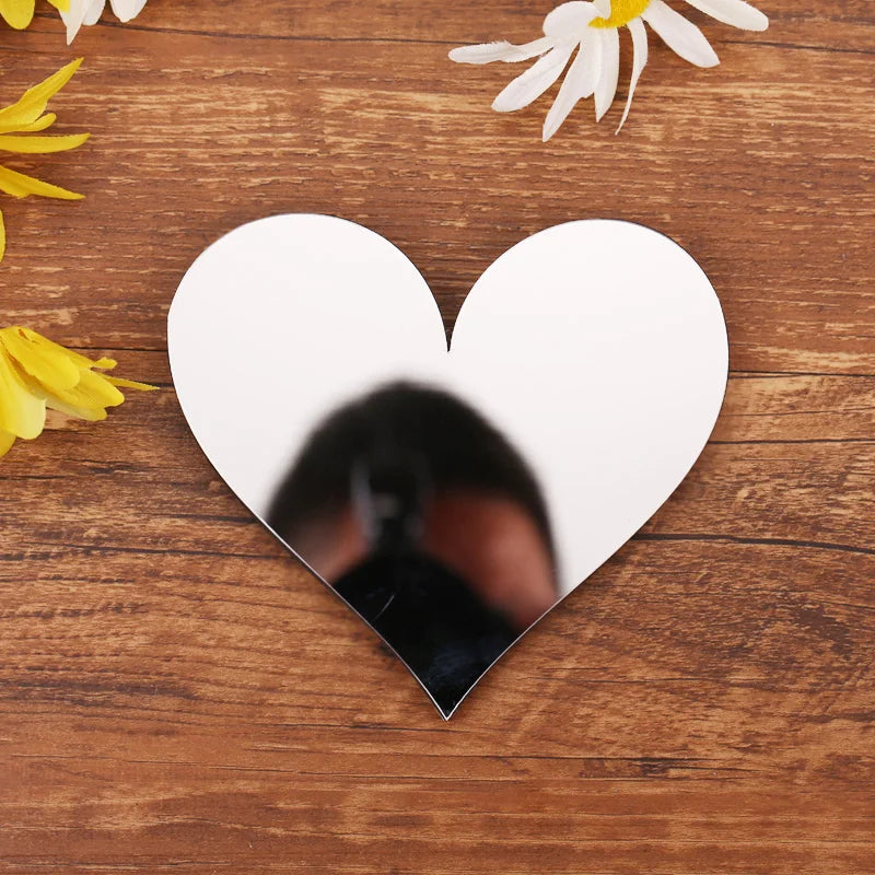 Silver mirror heart on a wooden table with flowers