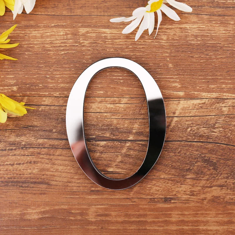 Letter O in silver mirror acrylic, 20 cm, on a wooden table with flowers