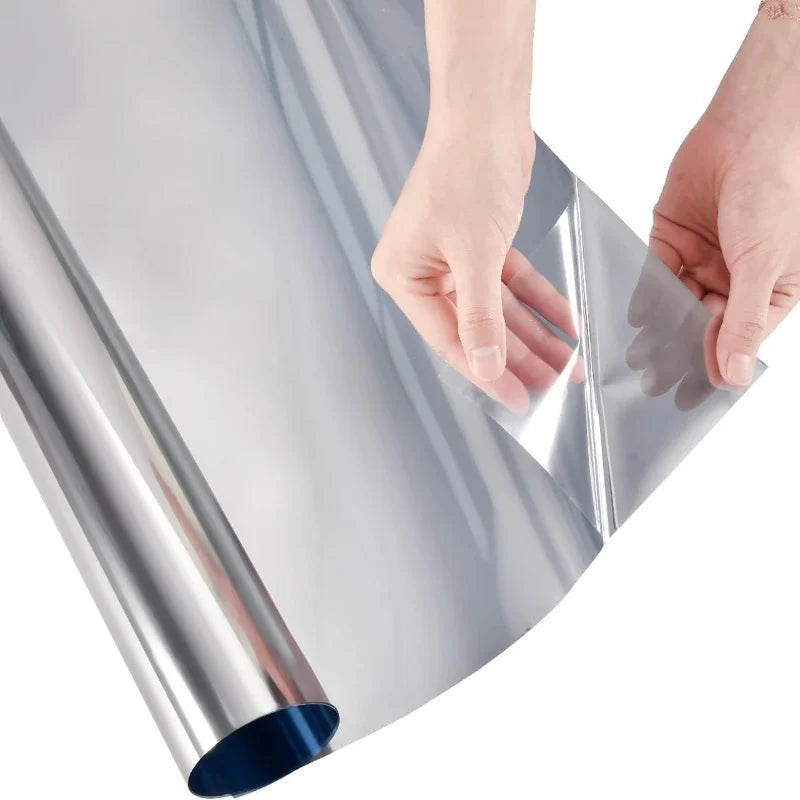Rol zilveren spiegelfolie voor glas, met de hand uitgerold op een witte achtergrond