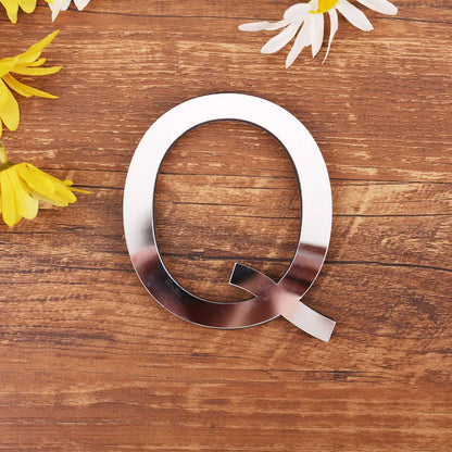 Letter Q in silver mirror acrylic, 20 cm, on a wooden table with flowers