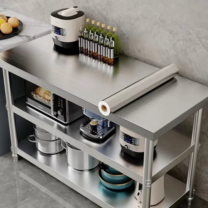 Metal kitchen table with shelves and a roll of vinyl resting on top