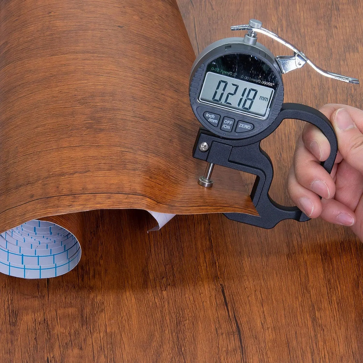 Brown wood effect vinyl wrap with a digital calliper reading 0.218 at the edge
